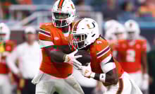 Cam Ward #1 of the Miami Hurricanes hands off the ball to teammate Mark Fletcher Jr. #4 during the first half of the game against the Virginia Tech Hokies at Hard Rock Stadium on Sept. 27, 2024, in Miami Gardens, Florida.