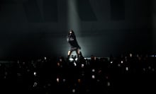 Charli XCX illuminated on stage.