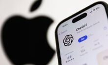 ChatGPT on AppStore displayed on a phone screen and Apple logo dislpayed on a screen in the background