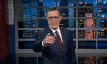 A man in a suit stands on a talk show stage, pointing at the camera.