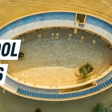 Aerial shot of the oval school amid the desert, solar panels seen on the roof. Caption reads: school oasis