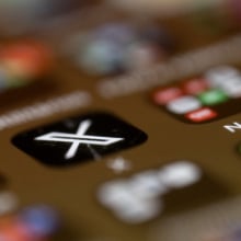 A blurry phone screen, with only the X app logo in focus.