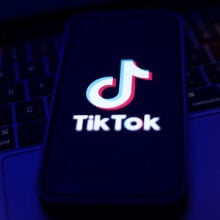TikTok logo displayed on a phone screen and a laptop keyboard