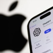 ChatGPT on AppStore displayed on a phone screen and Apple logo dislpayed on a screen in the background
