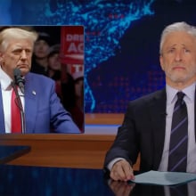A man sits behind a talk show desk looking disappointed. In the top left is an image of another man standing at a podium, surrounded by a crowd.