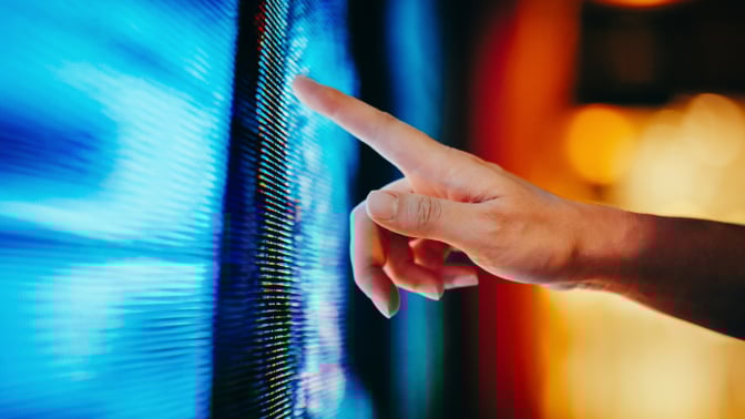 Close up of woman's hand touching illuminated and multi-coloured LED display screen
