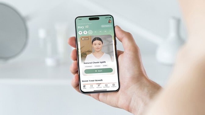 woman holding phone with Luvly Face Yoga app on screen