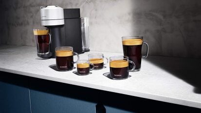 black and silver coffee machine with six cups of coffee on table