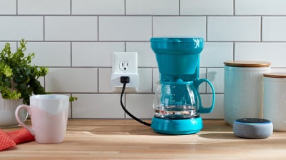 Blue coffee machine plugged into wall on table with cup