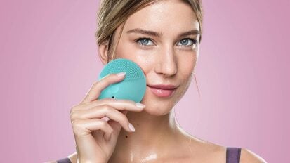 person holding blue face washing machine to face