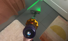 Hand cleaning tile bathroom floor with Dyson V12 Detect Slim vacuum and green laser highlighting debris on floor