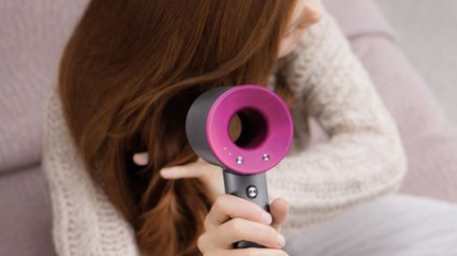 Person holding pink and grey hair dryer above hair