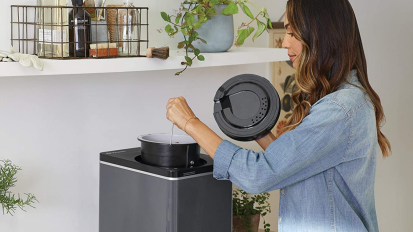 Person taking bucket out of grey composter on counter