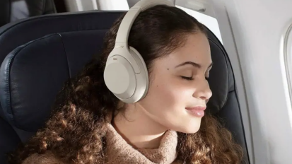 Person in airplane wearing white headphones and facing window