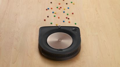 Black robot vacuum on wooden floor covered with candy